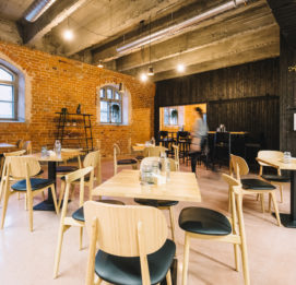 Ravintolasalin pöydät, taustalla ruskea tiilinen seinä ja musta puuseinä