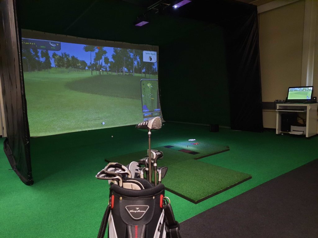 golfsimulaattori hotellilla, tekoviheriö ja projektorilla heijastettu golfkenttä