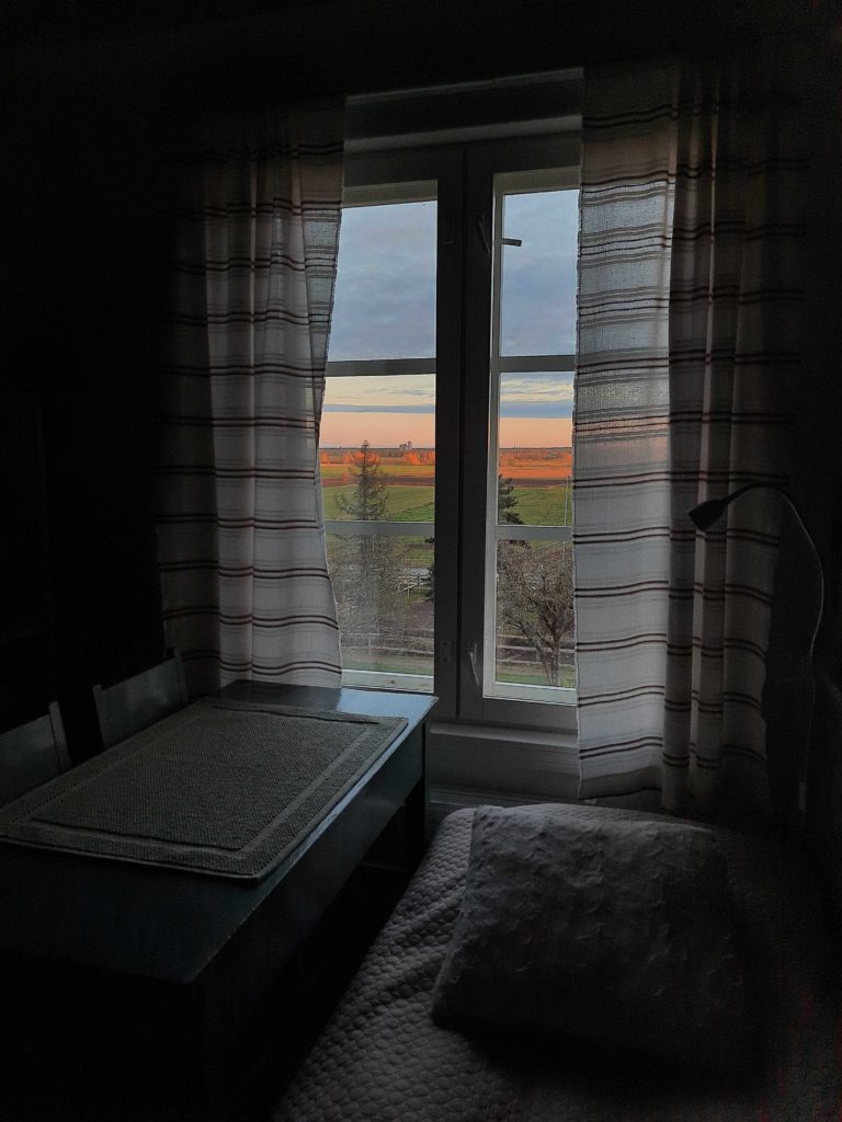 auringonnousu ikkunasta katsottuna lakeusmaisemilla