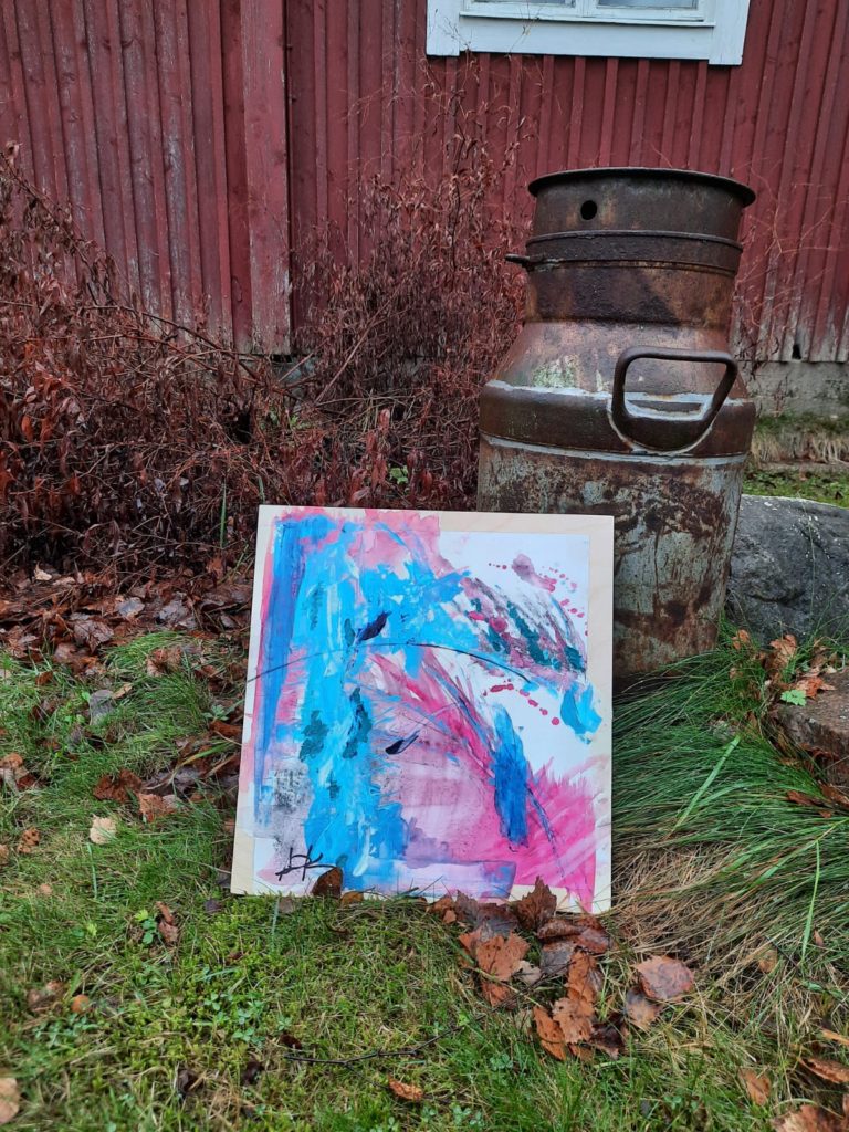 värikäs maalaus ruosteisen maitotonkan edessä nurmikolla ulkona