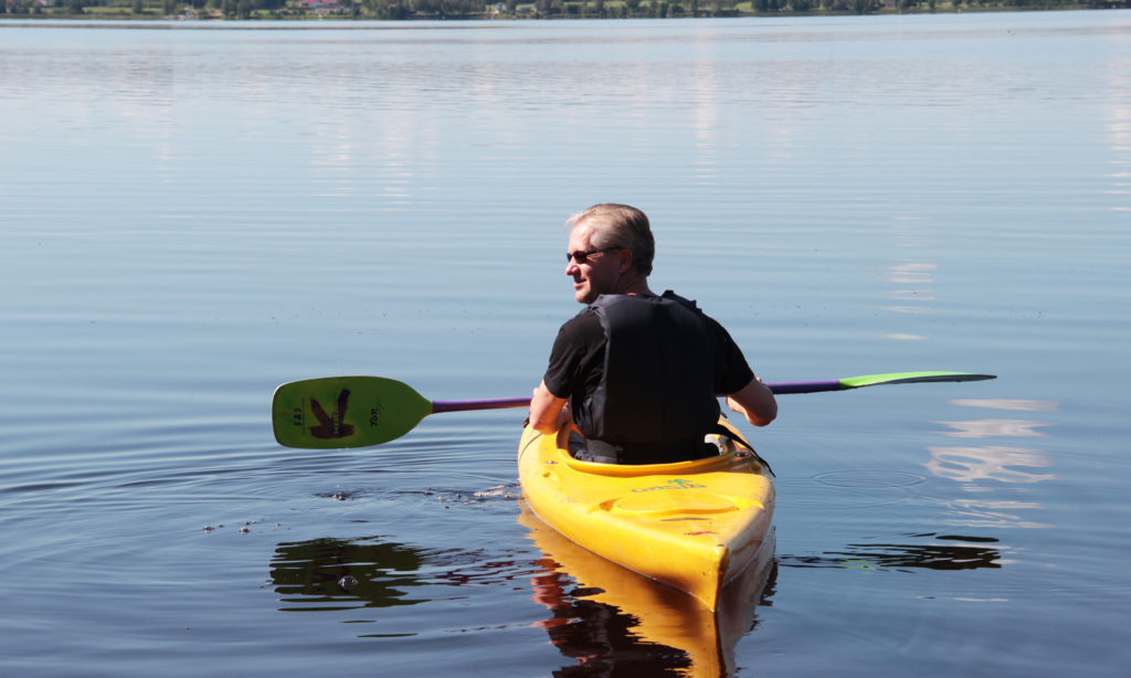 Mies lepää kanootin kyydissä järvellä Kuortaneenjärvellä