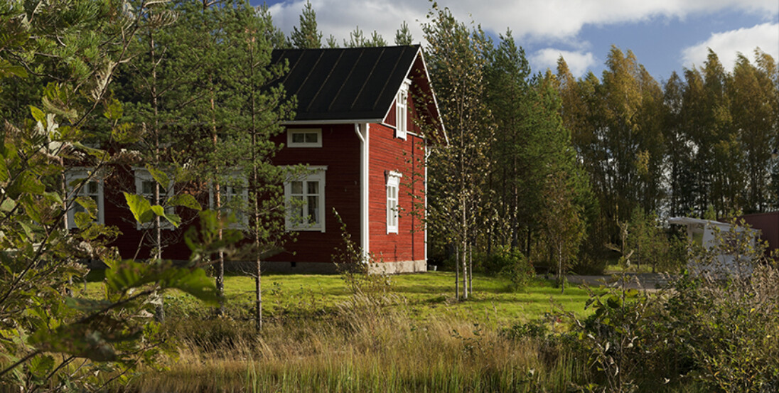 Suomen Siirtolaisuusmuseon Hakalantalo metsäisissä maisemissa järven vieressä.