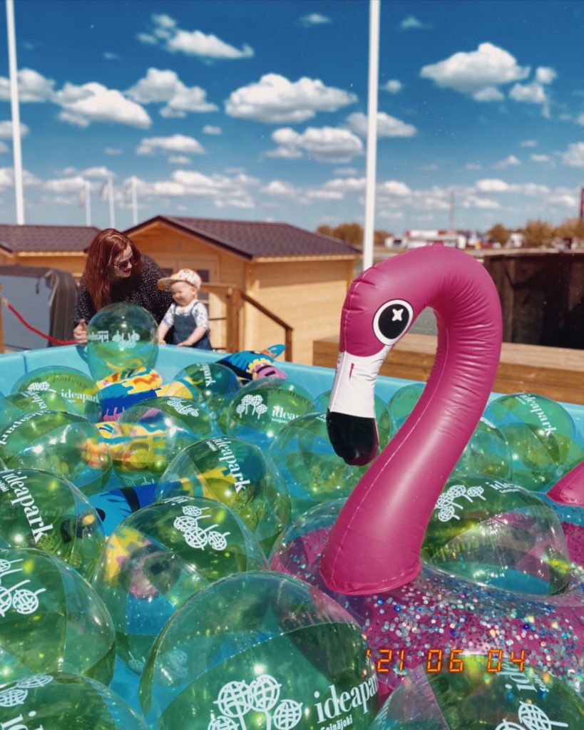 Rantapallot ja flamingo uimapatja altaassa. Äiti ja lapsi taustalla