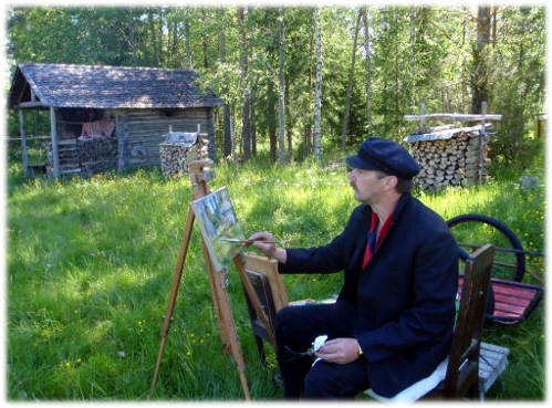 Taiteilija Reijo Kivijärvi maalaa. Vanha lato ja metsä taustalla