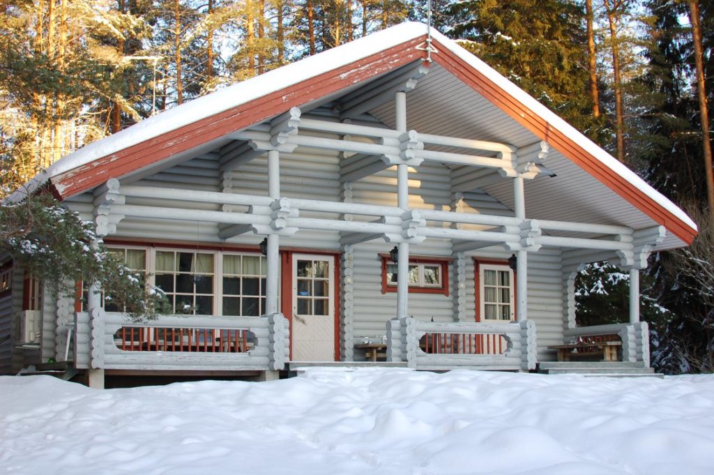 Kalajärven Lomakylän Aurinkolinna kuvattuna talvella. Lunta mökin katolla, metsä taustalla.