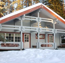 Kalajärven Lomakylän Aurinkolinna kuvattuna talvella. Lunta mökin katolla, metsä taustalla.