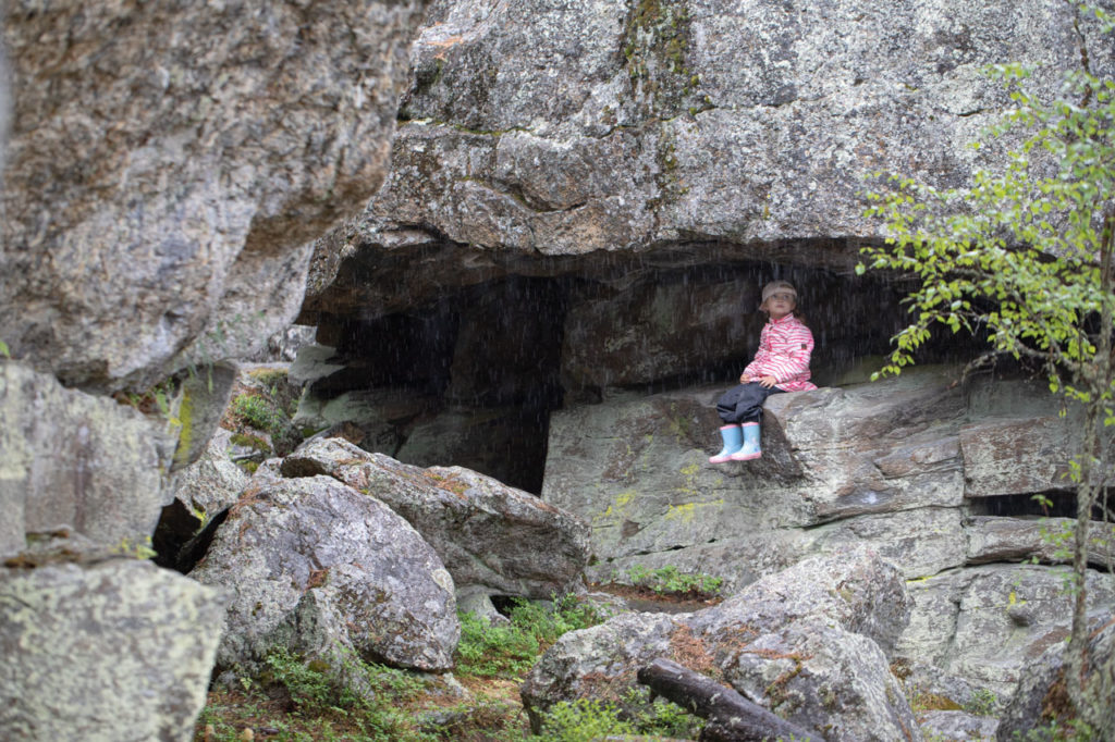 Lapsi pitää sateelta suojaa kallion alla Pyhävuori-Lakeaharjulla.