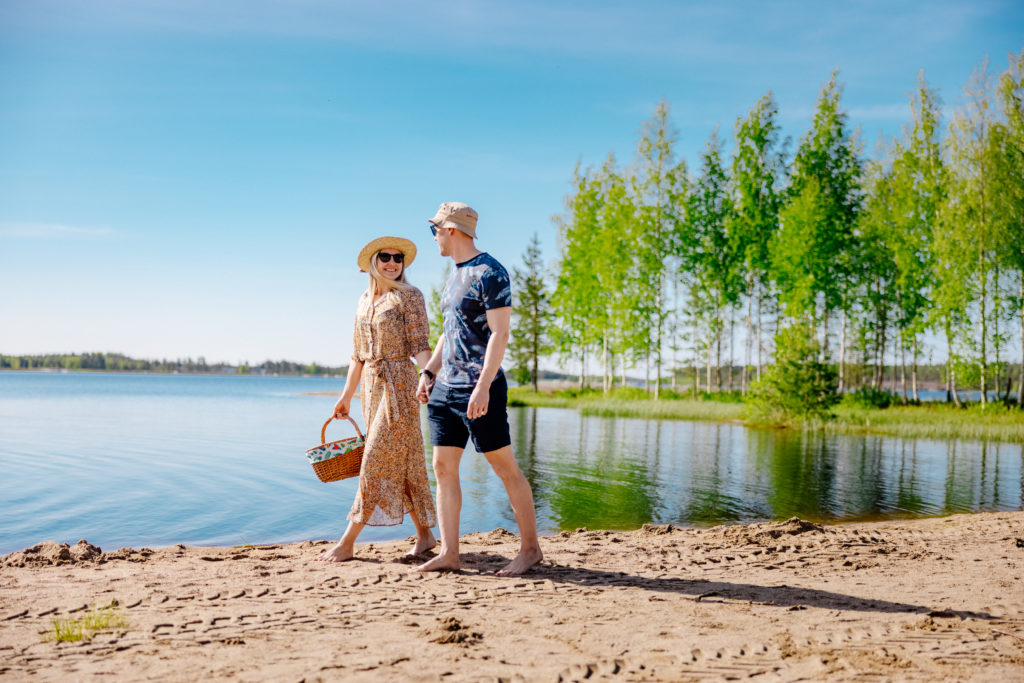 Pariskunta kävelee Seinäjoen Kyrkösjärven uimarannalla.